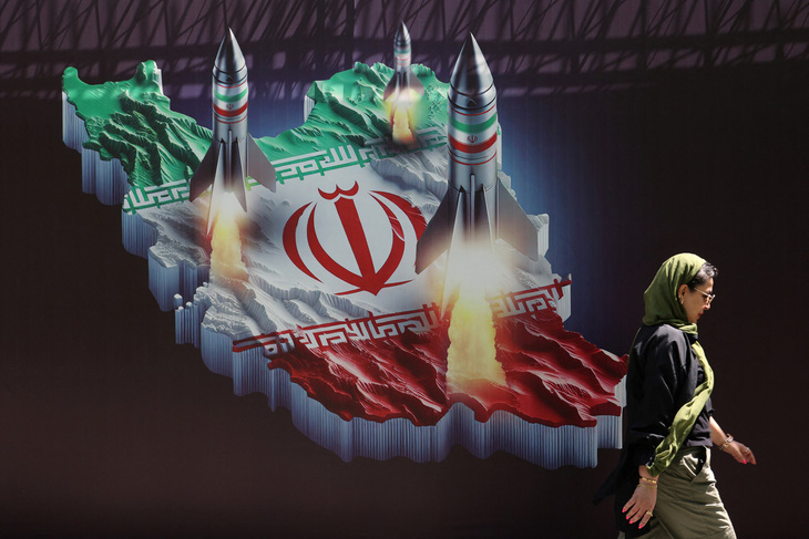 Một người dân Iran đi ngang qua tấm áp phích tại thủ đô Tehran thể hiện tiềm lực quốc phòng của Iran hôm 19-4 - Ảnh: REUTERS
