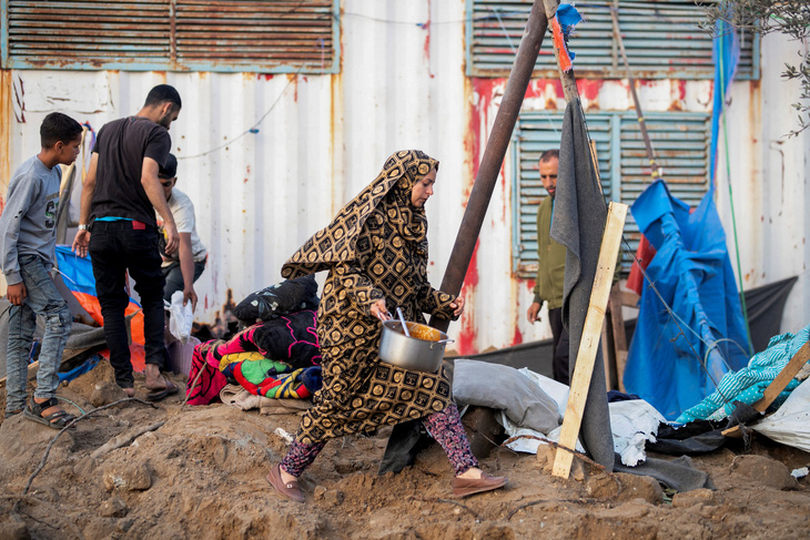 Một người phụ nữ bước đi khi những người Palestine khác kiểm tra địa điểm xảy ra cuộc tấn công của Israel ở Rafah, phía nam Dải Gazangày 22-4 - Ảnh: REUTERS