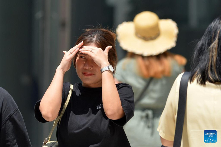 Một người đi bộ lấy tay che nắng khi đi ở Bangkok, Thái Lan - Ảnh: Xinhua