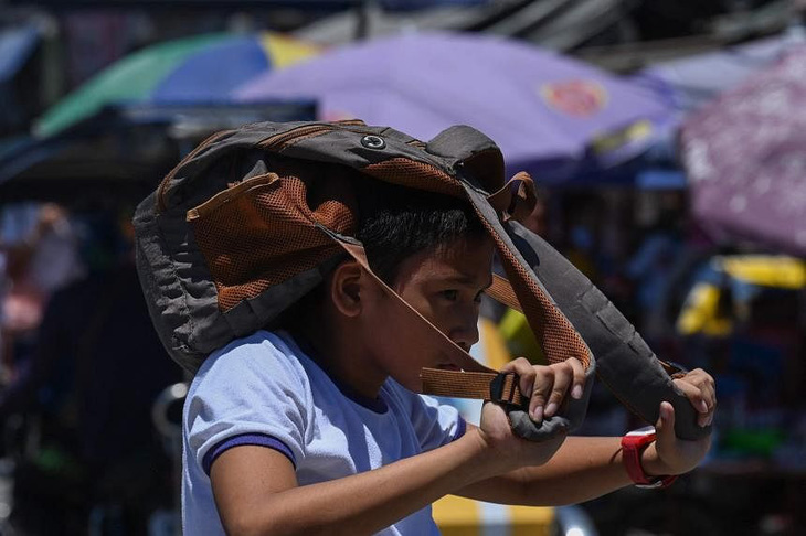 Một học sinh tại Manila lấy cặp để che đầu khi đến trường dưới thời tiết nắng nóng - Ảnh: AFP