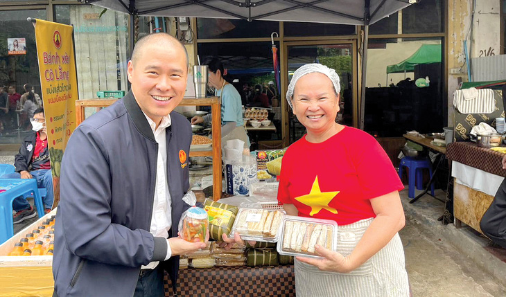 Anh Trần Văn Kiều (trái) chụp ảnh lưu niệm cùng một chủ cửa hàng trên tuyến phố Việt Nam - Ảnh: NVCC