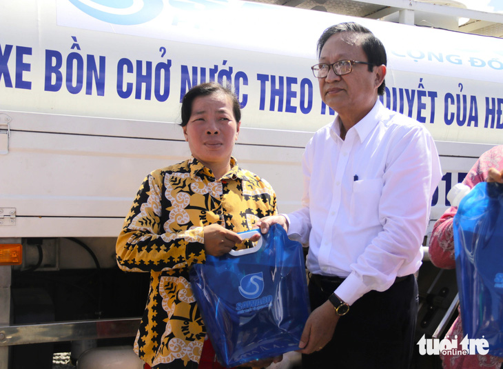 Ông Nguyễn Thanh Sử - phó tổng giám đốc Sawaco - cùng các lãnh đạo địa phương trao tặng túi nước sạch cho người dân xã Phú Đông - Ảnh: TIẾN QUỐC