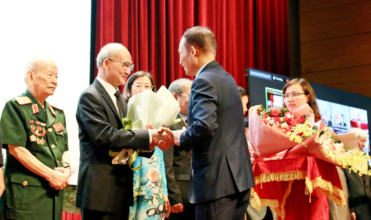 Ông Lê Hoài Trung, trưởng Ban Đối ngoại Trung ương, tặng hoa cho ông Phạm Sơn Dương và đại diện các gia đình thành viên đoàn đàm phán Hiệp định Geneve ngày 25-4 Ảnh: Báo Thế giới và Việt Nam
