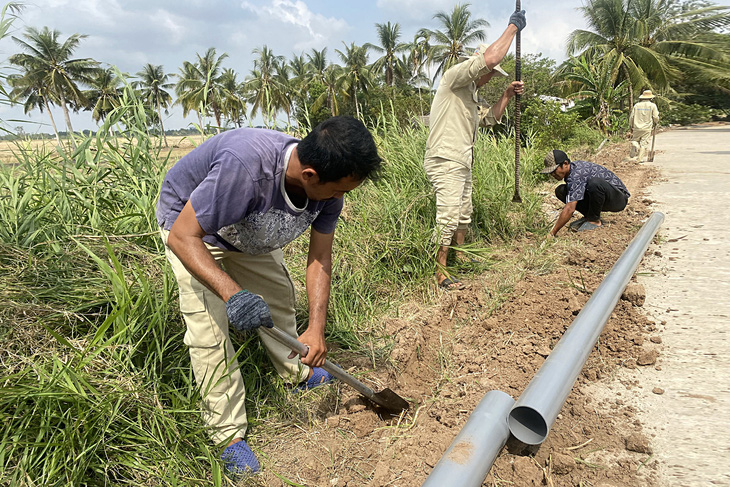 Các công nhân đang đào đường để mở rộng hệ thống ống dẫn nước, đem nước ngọt cho người dân ở ven biển của tỉnh Sóc Trăng - Ảnh: KHẮC TÂM