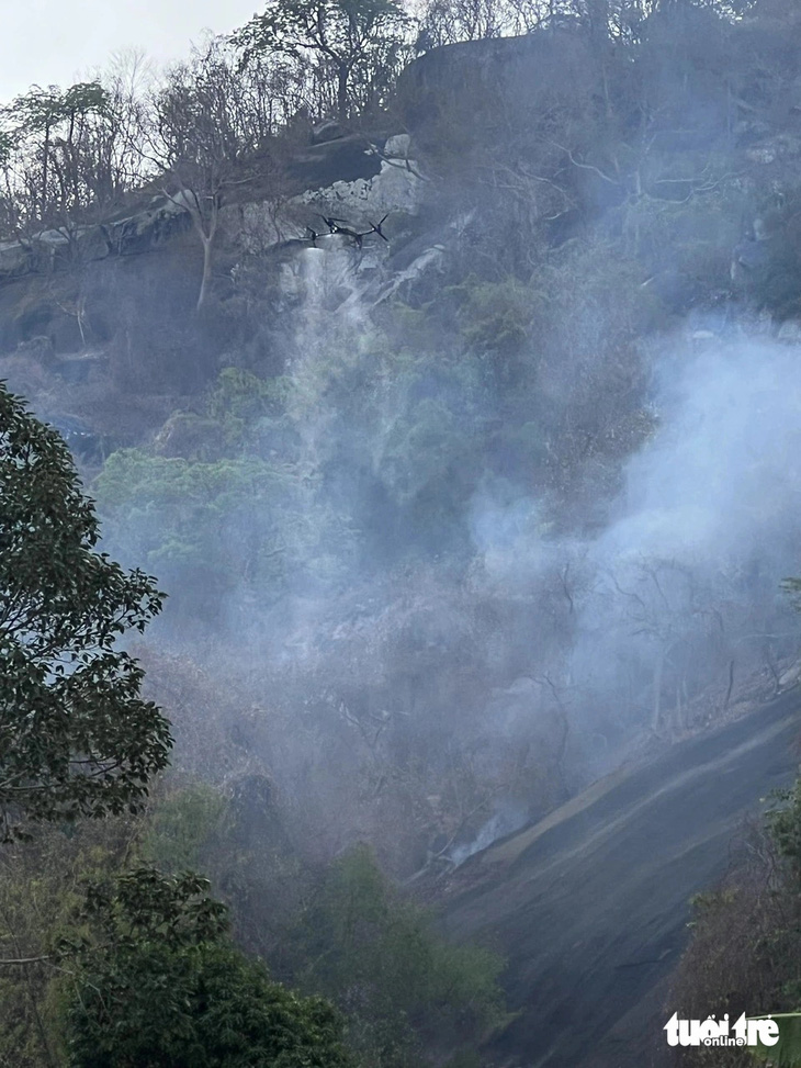 Lãnh đạo huyện Tri Tôn cho rằng do cháy cây cỏ thực bì len lỏi trên vách núi nên khó tiếp cận. Lực lượng chữa cháy phải dùng drone để dập các điểm có khói nghi ngút - Ảnh: MINH KHANG