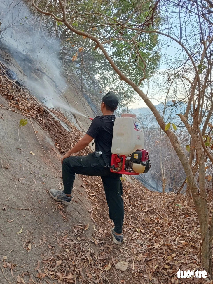 Dùng bình chữa cháy ở các điểm khó tiếp cận ở núi Cô Tô - Ảnh: MINH KHANG