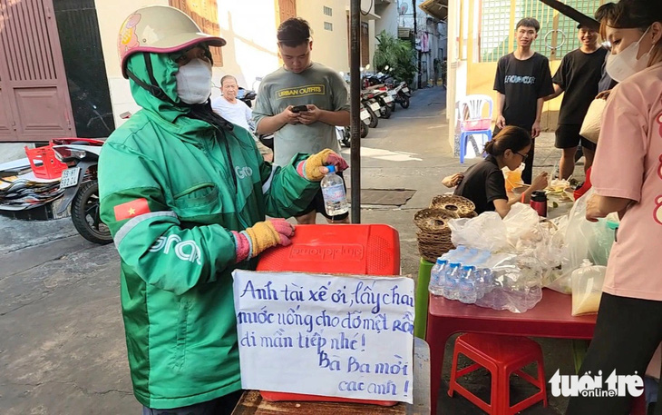 Chị Hồ Thị Thúy An lấy chai nước từ chiếc thùng mà quán mời tài xế - Ảnh: NGỌC KHẢI