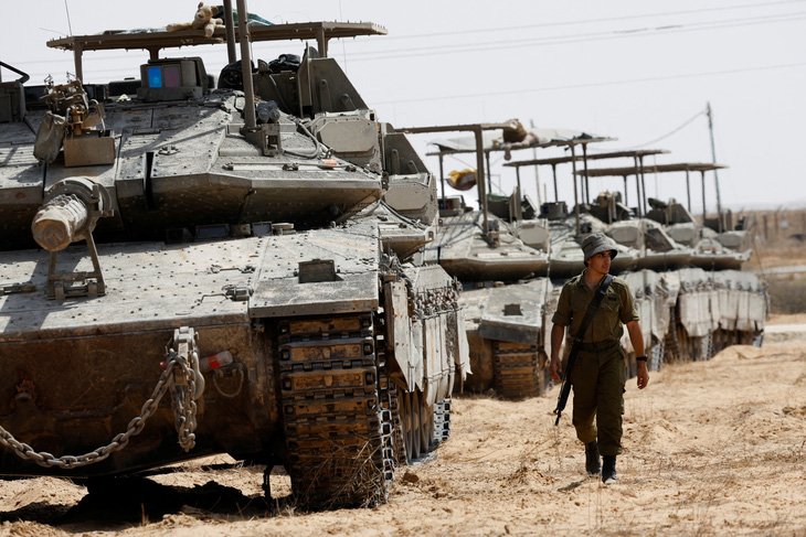 Binh sĩ Israel đi gần xe tăng đậu gần biên giới Israel - Dải Gaza trong ảnh chụp ở phía Israel ngày 28-4 - Ảnh: REUTERS