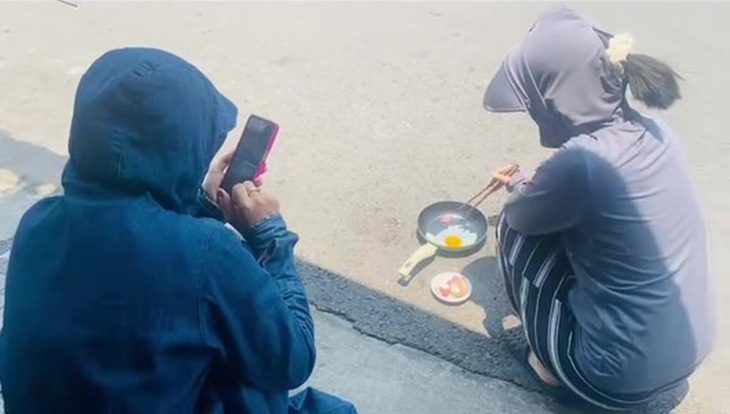 Người dân ở huyện Quế Sơn đặt chảo ra ngoài mặt đường lúc trời nắng nóng để rán trứng - Ảnh cắt từ clip