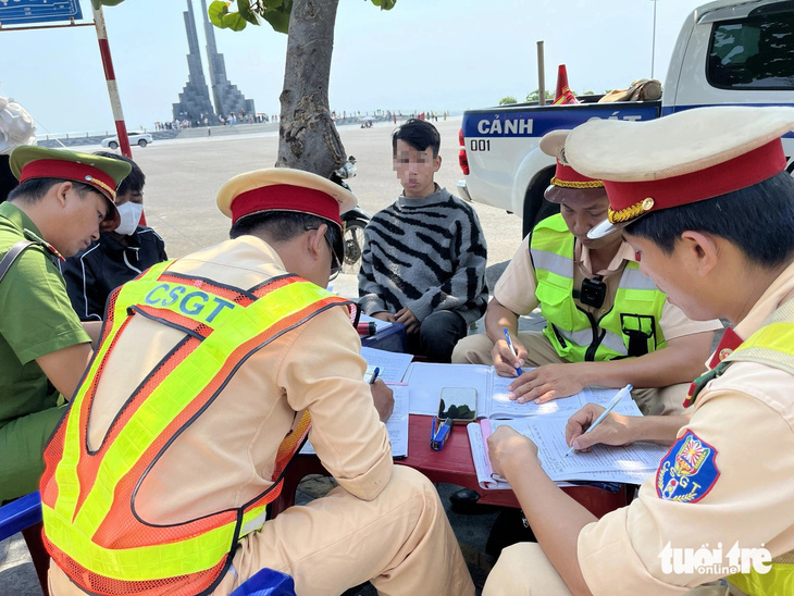 Cảnh sát giao thông lập biên bản xử phạt các quái xế dùng xe độ chạy ở quảng trường tháp Nghinh Phong - Ảnh: NGUYỄN HOÀNG