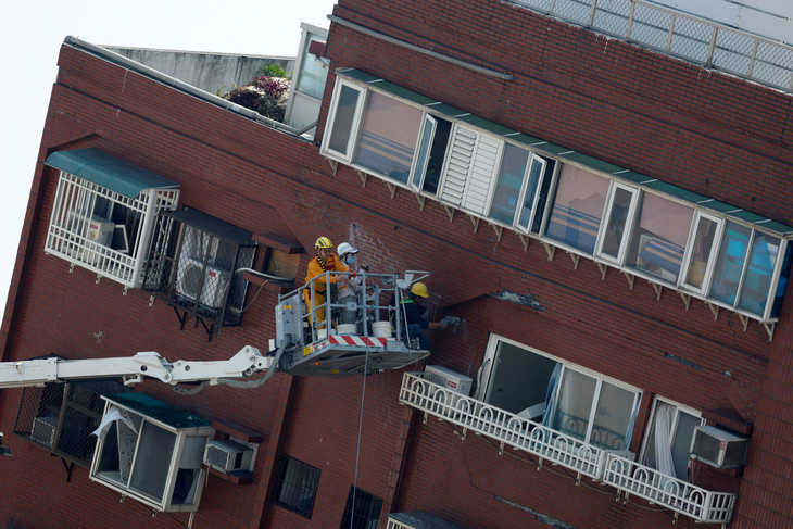 Các công nhân làm việc tại hiện trường một tòa nhà bị nghiêng đổ do động đất ở Hoa Liên, Đài Loan vào sáng 4-4 - Ảnh: REUTERS
