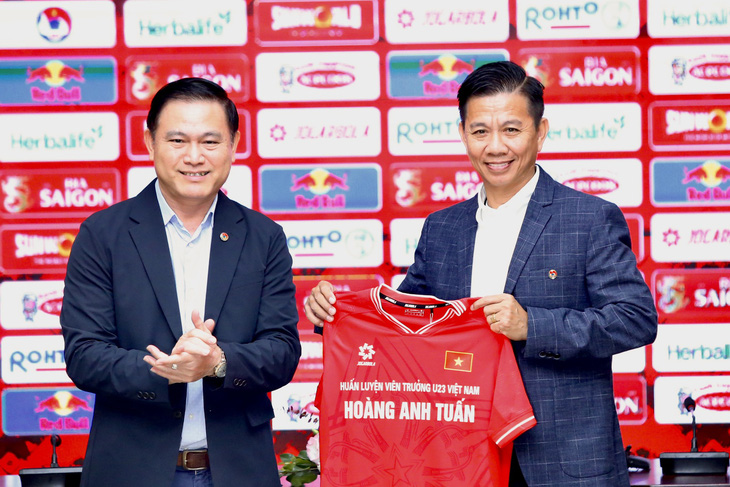 Ông Trần Anh Tú (bìa trái) trao áo và giao nhiệm vụ cho HLV trưởng đội U23 Việt Nam Hoàng Anh Tuấn - Ảnh: HOÀNG TÙNG