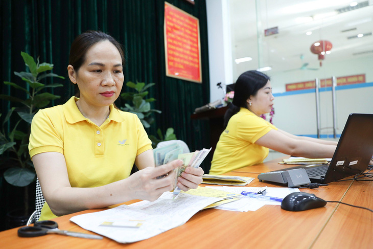 Cán bộ ngành bưu điện kiểm tiền trước khi chi trả lương hưu, trợ cấp bảo hiểm xã hội cho bà con tại một điểm chi trả tại Đống Đa, Hà Nội - Ảnh: DANH KHANG