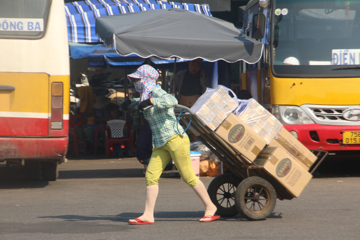 Đối chọi với cái nắng nóng như đổ lửa, người lao động nghèo ở chợ Đông Ba (TP Huế) thường chọn cách mặc kín từ đầu đến chân để chống nắng - Ảnh: BẢO PHÚ