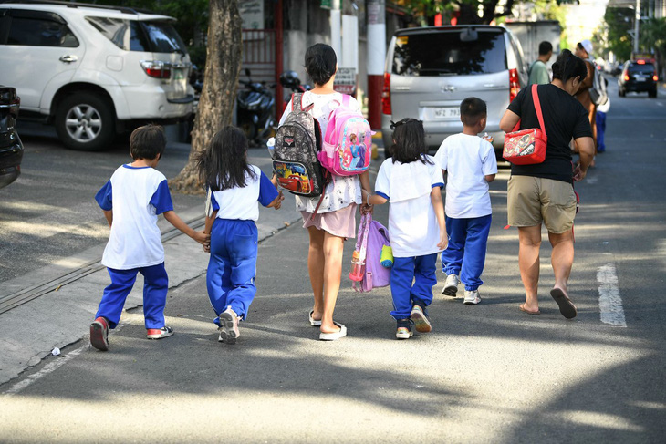 Phụ huynh dẫn con từ trường về tại thủ đô Manila, Philippines ngày 5-4 - Ảnh: AFP