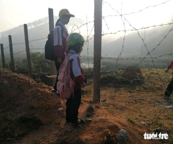 2 em học sinh chuẩn bị chui rào để đến trường - Ảnh: M.V.