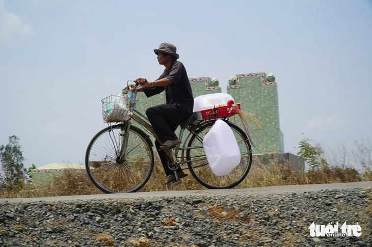 Ông Nguyễn Văn Hải, 50 tuổi, ngụ huyện Gò Công Đông, đạp xe chở theo 2 can nước loại 30 lít đi xin nước từ xe bồn từ thiện. Ông Hải cho biết hai ngày qua, gia đình ông chưa có nước để xài - Ảnh: MẬU TRƯỜNG