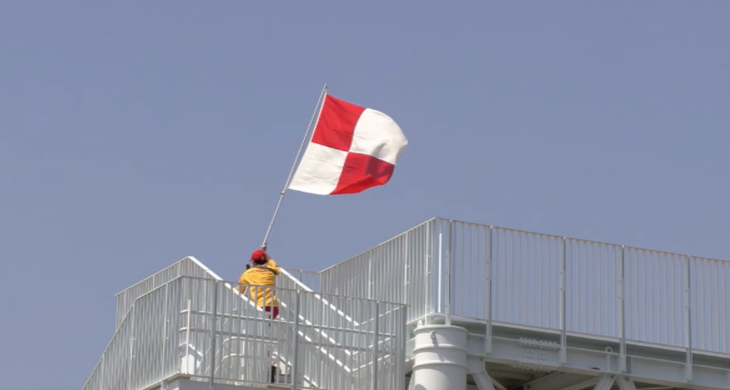 Một nhân viên cứu hộ Nhật Bản vẫy lá cờ cảnh báo sóng thần - Ảnh: JMA