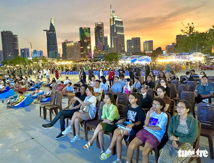 Người dân ngồi ghế nhựa, ghế lười đợi xem chương trình khai mạc điểm chiếu phim ngoài trời ở công viên bờ sông Sài Gòn - Ảnh: T.D.D.