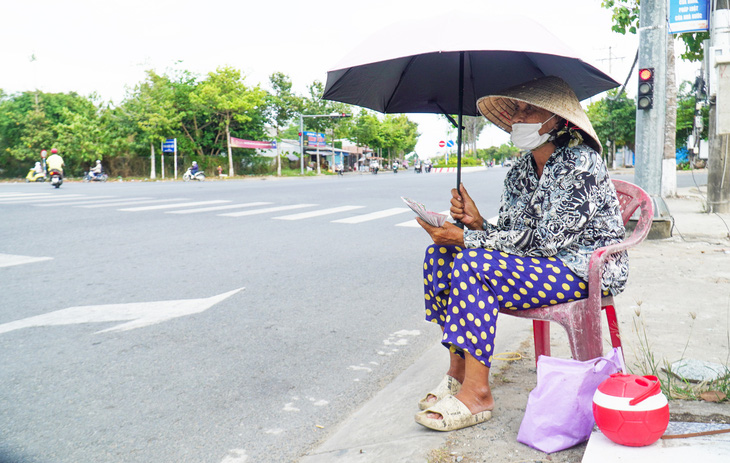 Bà Trương Thị Đen (70 tuổi, tỉnh Cà Mau) mỗi ngày phải phơi nắng khoảng 10 giờ, cạnh trụ đèn giao thông, để bán 200 tờ vé số - Ảnh: THANH HUYỀN