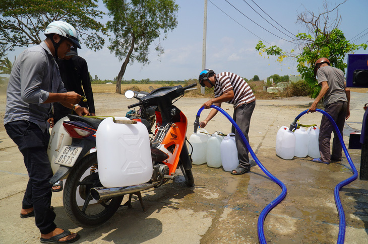 Người dân hứng nước tại một điểm cho nước ở huyện Gò Công Đông - Ảnh: MẬU TRƯỜNG