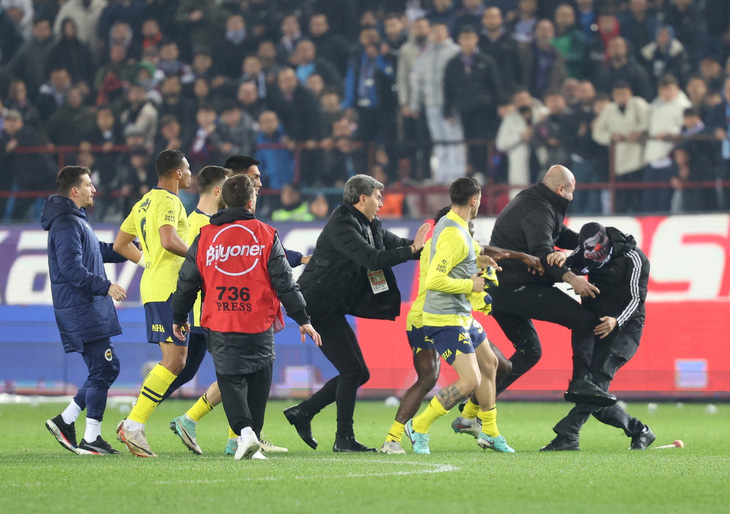 Cầu thủ Fenerbahce và các CĐV Trabzonspor đụng độ ở Giải vô địch Thổ Nhĩ Kỳ - Ảnh: REUTERS