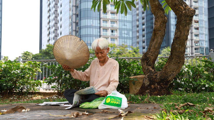 Bà Phạm Thị Ngọc ra bờ kè kênh Nhiêu Lộc - Thị Nghè, đọc báo để tránh nóng