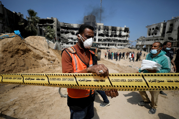 Một người đàn ông phong tỏa khu vực khi lực lượng cứu hộ và y tế tìm kiếm thi thể bên trong Bệnh viện Al Shifa, sau khi lực lượng Israel rút khỏi bệnh viện và khu vực xung quanh tại thành phố Gaza, Dải Gaza, ngày 8-4 - Ảnh: REUTERS