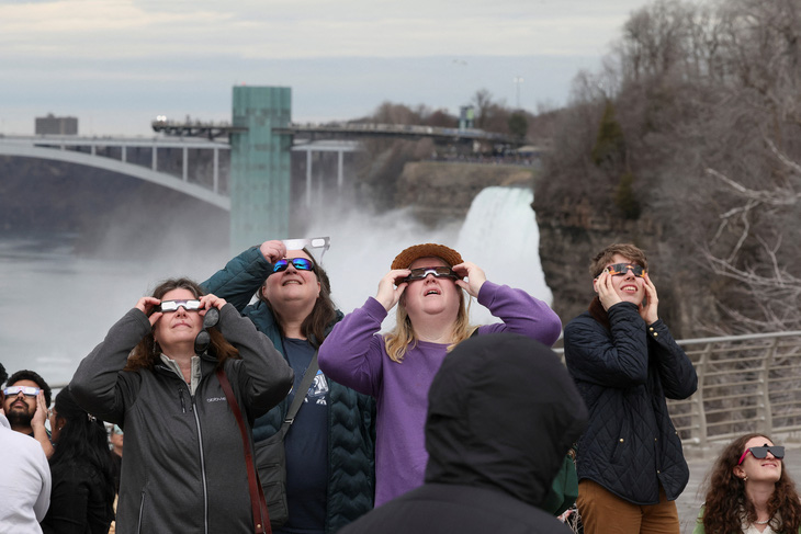 Dù trời nhiều mây nhưng rất đông người dân vẫn chăm chú xem nhật thực ở thác Niagara, thành phố New York, Mỹ - Ảnh: REUTERS