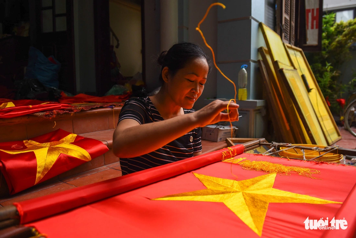 Một người phụ nữ làm nghề thêu cờ tại làng Từ Vân (Lê Lợi, Thường Tín, Hà Nội) - Ảnh: HOÀNG THANH TÙNG