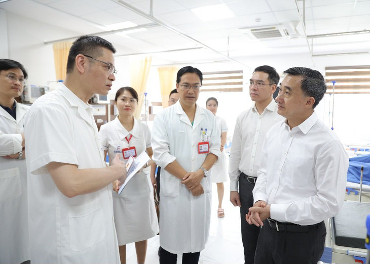 Hôm 9-5, Thứ trưởng Bộ Y tế Trần Văn Thuấn đã đến thăm bác sĩ Lý tại bệnh viện. Trong ảnh, Thứ trưởng Thuấn (bìa phải) đang trao đổi với các bác sĩ Bệnh viện Đại học Y Hà Nội, nơi đang điều trị cho bác sĩ Hoàng Minh Lý  - Ảnh: TRẦN MINH