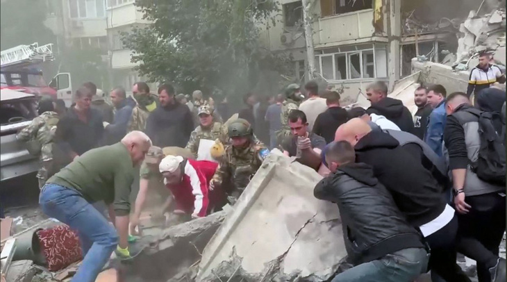 Người dân dọn dẹp đống đổ nát của tòa nhà bị sập sau khi trúng mảnh vỡ của tên lửa Ukraine tại thành phố Belgorod (Nga) ngày 12-5 - Ảnh: AFP/@VVGLADKOV
