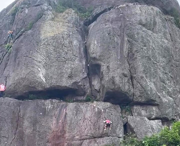 Hai người tay không bám sợi dây thừng leo lên núi Hòn Chuông rất nguy hiểm - Ảnh cắt từ video trên fanpage Bình Định Thông Tin