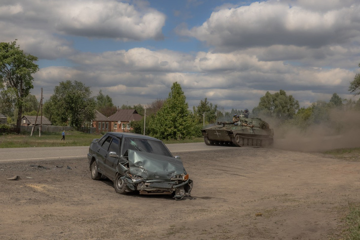 Pháo tự hành 2S1 Gvozdika của Ukraine băng qua một chiếc ô tô bị hư hỏng trên đường phố ở Vovchansk, vùng Kharkov, đông bắc Ukraine, ngày 12-5 - Ảnh: AFP
