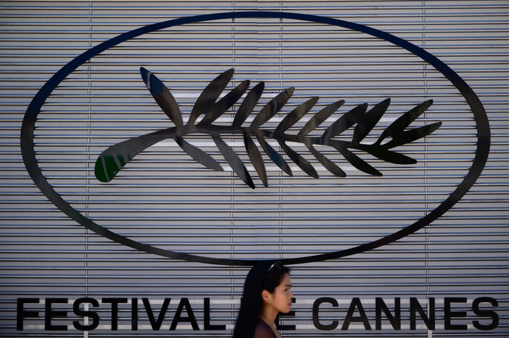 Một khách bộ hành đi ngang qua logo chính thức của Liên hoan phim Cannes lần thứ 77 ngày 13-5. Liên hoan phim uy tín bậc nhất thế giới này sẽ diễn ra từ 14-25 tháng 5 - Ảnh: AFP