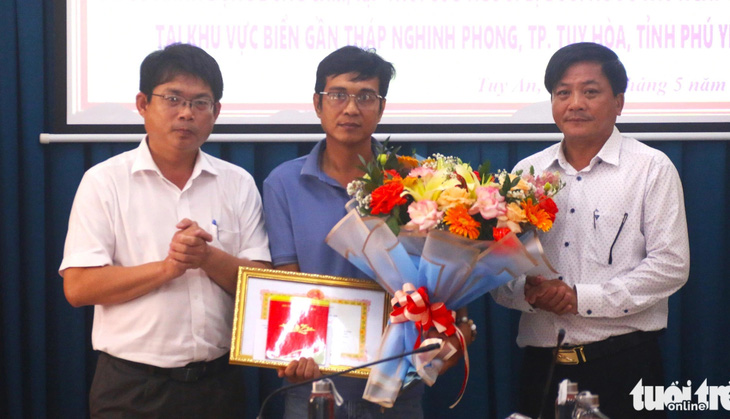 Chủ tịch UBND huyện Tuy An Huỳnh Gia Hoàng (ngoài cùng bên trái) trao bằng khen cho anh Trần Văn Tính (giữa) vì có hành động dũng cảm cứu người bị đuối nước - Ảnh: NGUYỄN HOÀNG