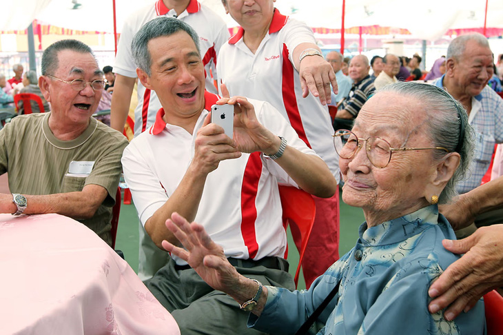 Thủ tướng Lý Hiển Long chụp ảnh bà Yeo Kheng Lien (98 tuổi) trong chương trình trao tặng hồng bao trị giá 100 USD cho 350 người có hoàn cảnh khó khăn ngày 15-1-2012 - Ảnh: SEAH KWANG PENG/THE STRAITS TIMES