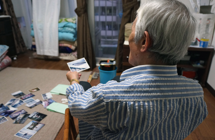 Một người đàn ông lớn tuổi tại thành phố Tokyo, Nhật Bản với những bức hình hồi ông còn trẻ - Ảnh: KYODO