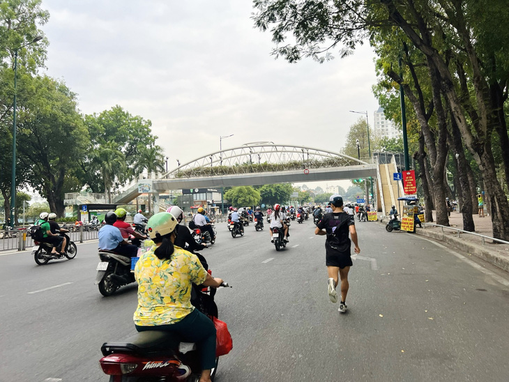 Một thanh niên chạy bộ "đua" với xe máy trên đường Hoàng Minh Giám, quận Gò Vấp - Ảnh: XUÂN ĐOÀN