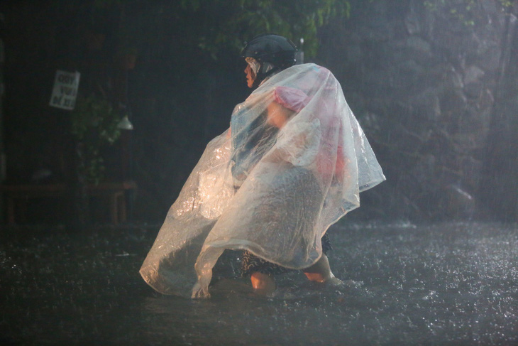 Một trẻ em được đón về giữa cơn mưa - Ảnh: PHƯƠNG QUYÊN