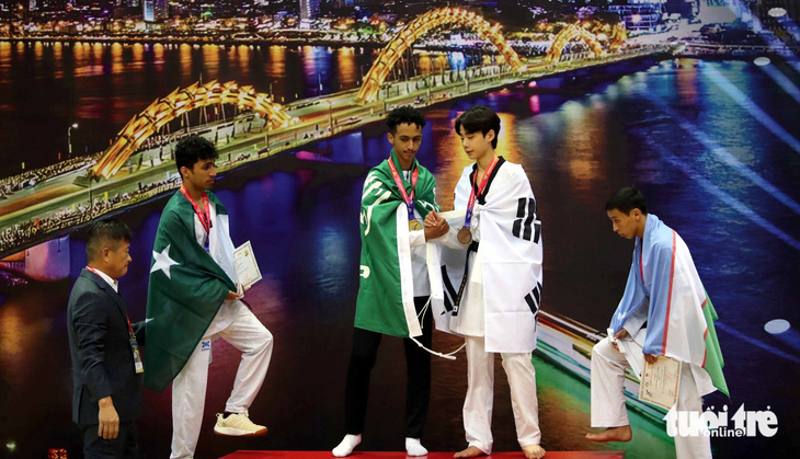 Hamdi Riad chủ động bắt tay Yang Hui Chang khi cùng nhau đứng chụp hình trên bục nhận huy chương - Ảnh: N.K