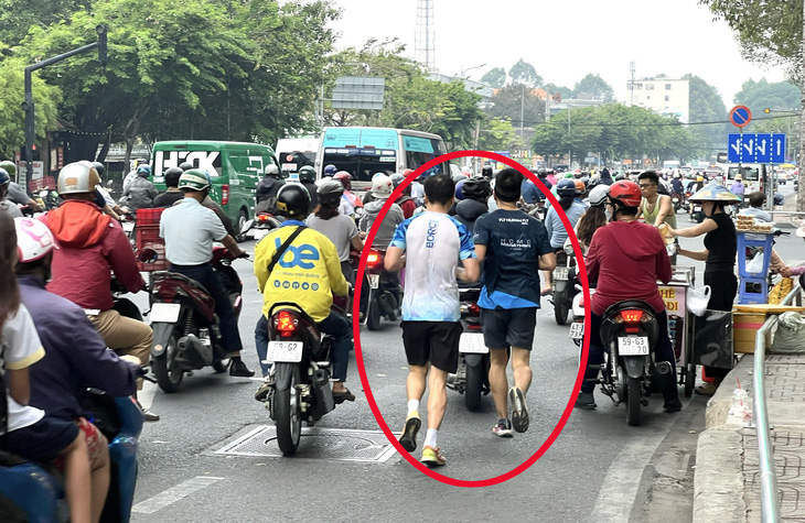 Hai người chạy bộ len lỏi giữa dòng xe trên đường Hoàng Minh Giám, quận Gò Vấp - Ảnh: XUÂN ĐOÀN