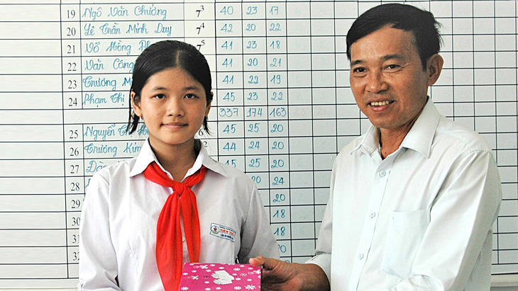 Thầy Hồ Văn Việt tặng thưởng cho Lâm Ân Phước khi bạn đạt học sinh giỏi - Ảnh: LƯ THẾ NHÃ