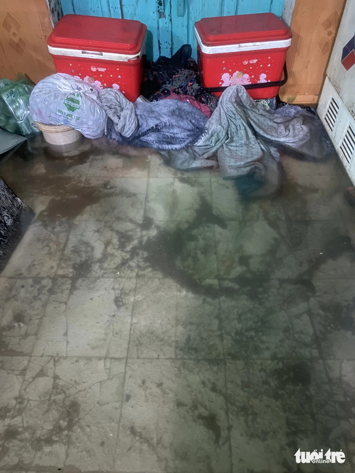 Một hộ dân dùng các vật dụng trong nhà để chặn bùn đen tràn vào nhà 