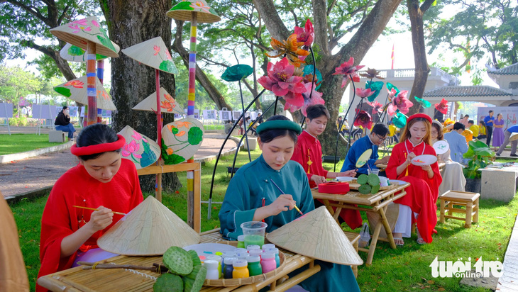 Nhóm sinh viên Trường đại học Đồng Tháp tham gia vẽ tranh sen trên nón lá, tranh sen lên quạt tại công viên Văn Miếu - Ảnh: ĐẶNG TUYẾT