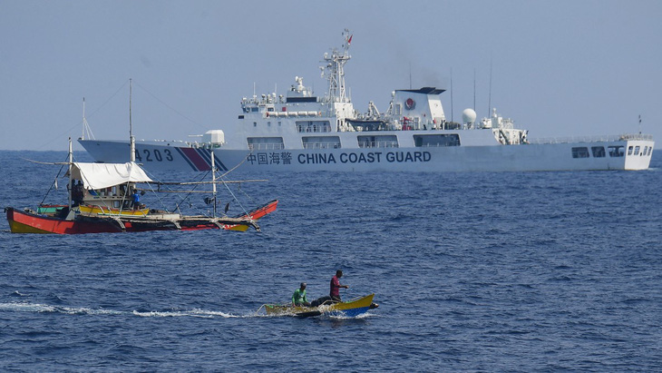 Một tàu hải cảnh Trung Quốc giám sát tàu dân sự tham gia tiếp tế cho ngư dân Philippines ở Biển Đông ngày 16-5 - Ảnh: AFP