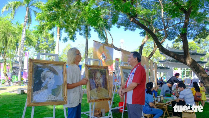 Ông Lê Văn Nghĩa (bìa trái) thuyết minh với khách tham quan triển lãm tranh sen tại Lễ hội sen Đồng Tháp lần thứ 2 - Ảnh: ĐẶNG TUYẾT