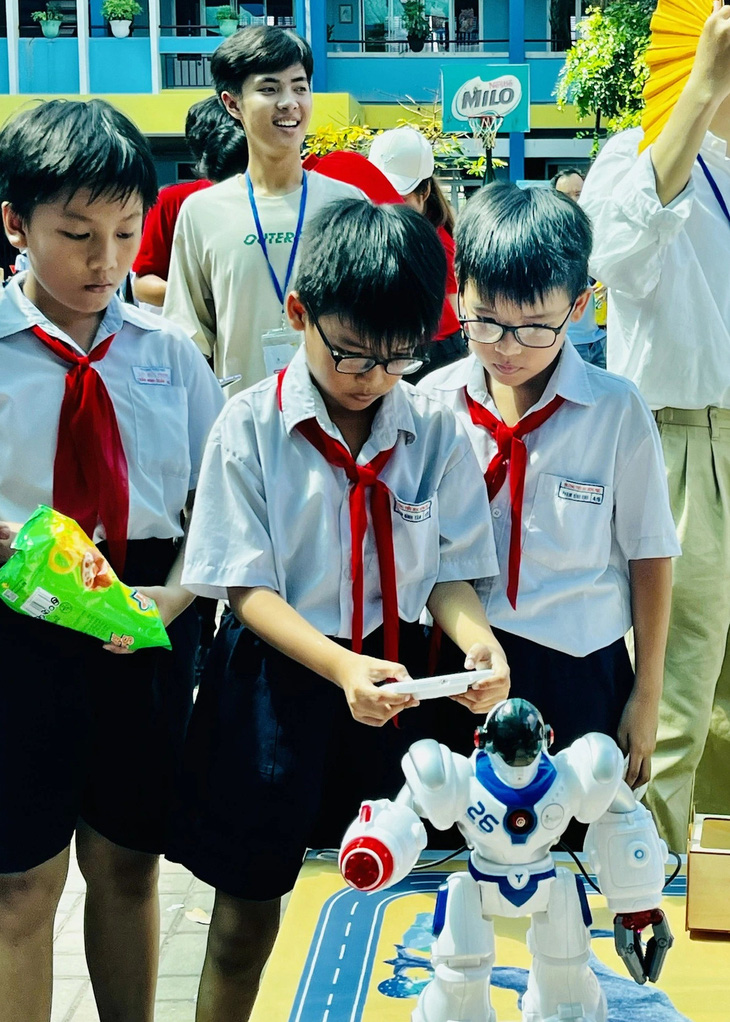 Các em học sinh tiểu học chăm chú điều khiển robot tại ngày hội "Em là công dân số" - Ảnh: MỸ DUNG