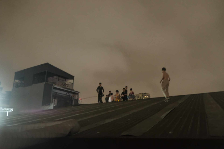 Nhiều người leo lên mái nhà chờ giải cứu - Ảnh: NGUYỄN GIANG