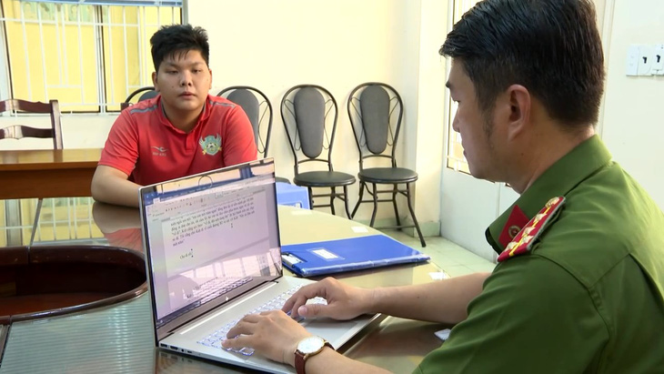 Nguyễn Khoa Minh (áo cam) tại cơ quan công an - Ảnh: Công an cung cấp